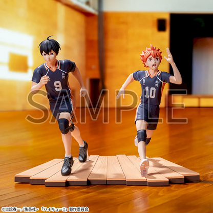 Two anime character figurines in volleyball uniforms on a wooden platform.