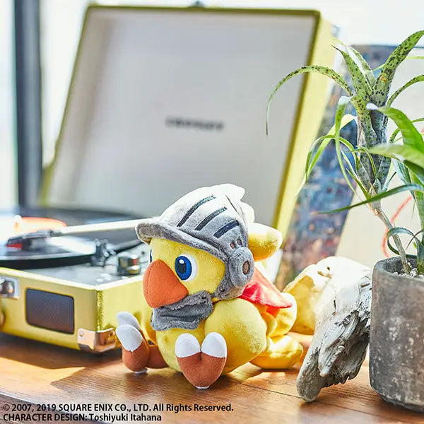 Plush toy resembling a dragon with armor on a desk next to a vinyl record player and plant.