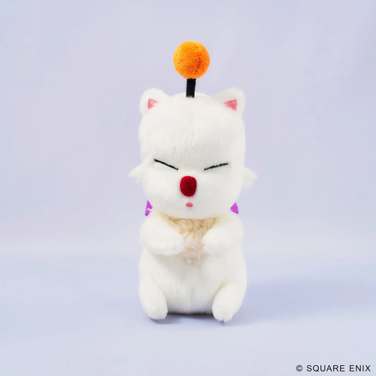 A white plush cat character toy with closed eyes, a red nose, pink inner ears, a small orange pom-pom on a black stick, and purple triangular accents, centered on a pale lavender studio background. A small Square Enix copyright mark appears in the bottom right corner.