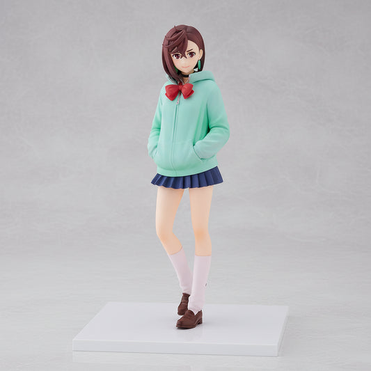 Figurine of a character wearing a green hoodie with a red bow, blue skirt, and brown shoes on a white background.
