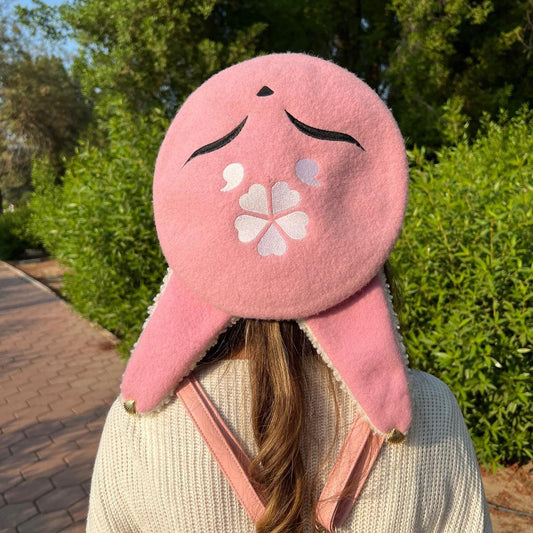 Person wearing a pink cartoon-like hat with a flower design outdoors.