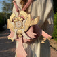 Person wearing a decorative pink and gold bag with a unique design.