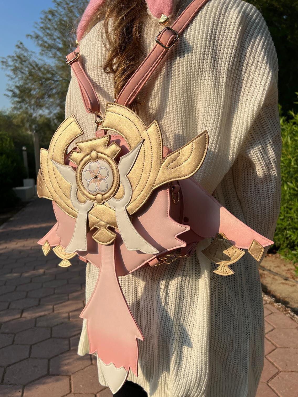 Person wearing a decorative pink and gold bag with a unique design.